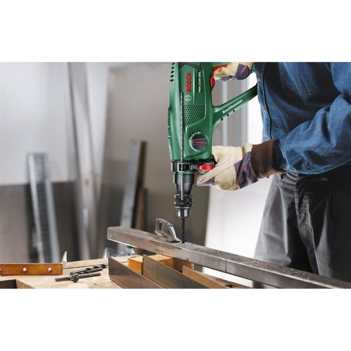 Un artisan perce du métal avec une perceuse Bosch verte.