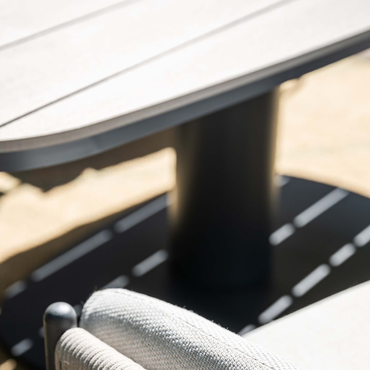 Deel van een moderne tafel en stoel met stoffering, buiten.