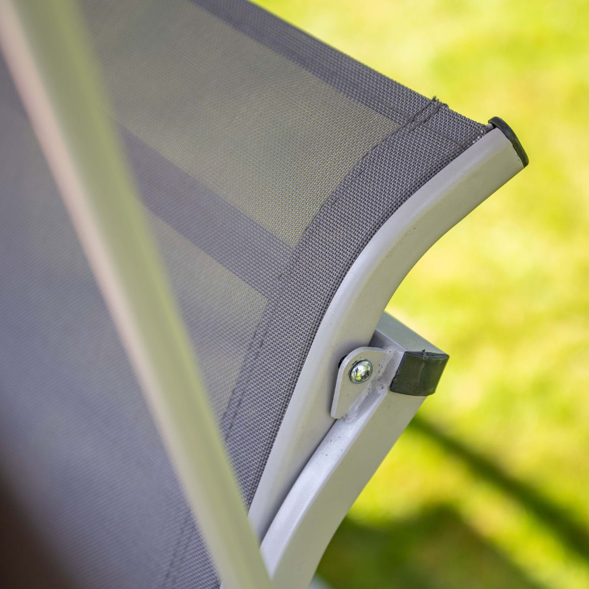 Grijs mesh stof op ligstoel met metalen frame, buiten op gras.
