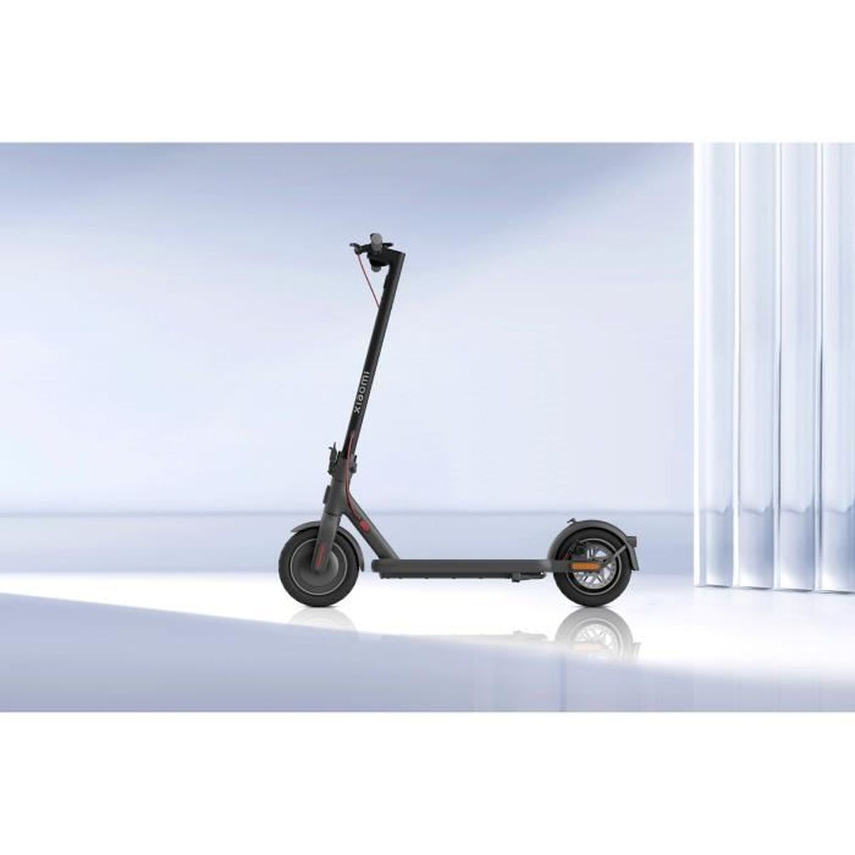 Un scooter électrique sombre avec des accents rouges se tient sur un sol blanc.