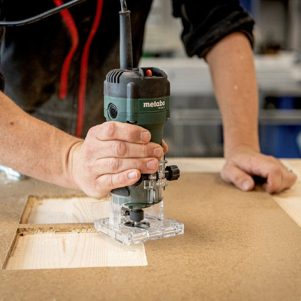 Ein Mann benutzt einen grünen Metabo-Fräser, um Holz zu bearbeiten.