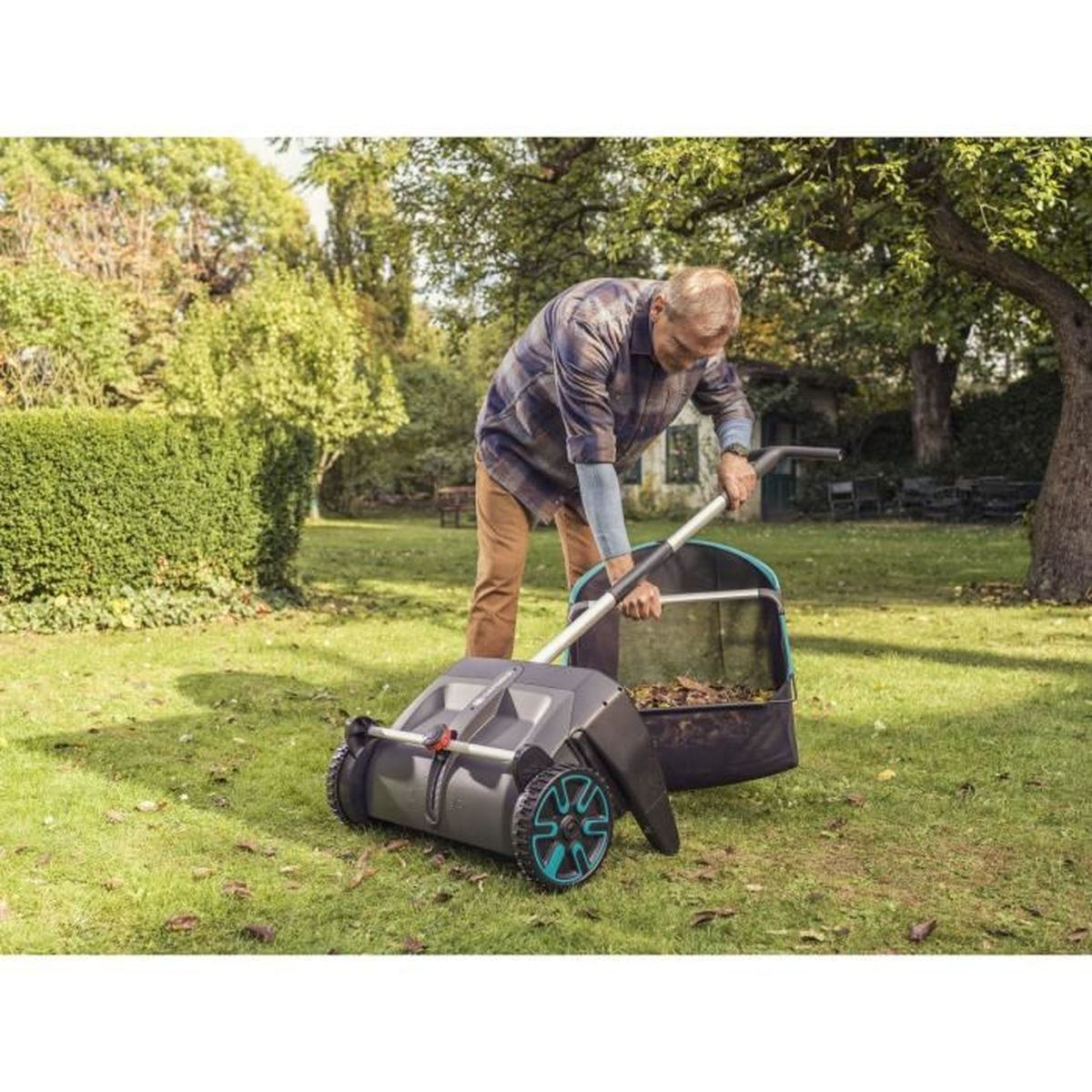 Mann benutzt Laubsammler im Garten mit Rasen und Bäumen.