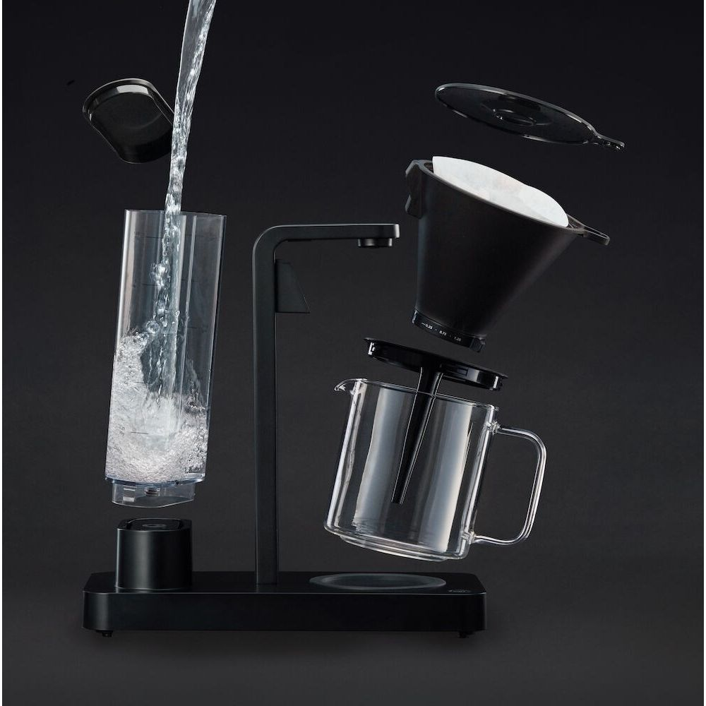Una macchina da caffè con parti smontate: l'acqua versa in una caraffa di vetro.