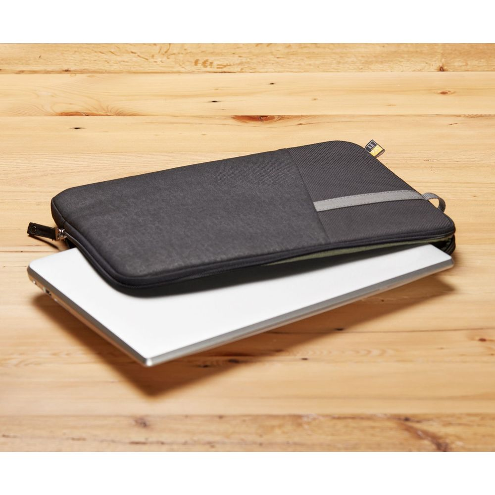 Un ordinateur portable repose sur une housse en tissu gris foncé sur une table en bois.