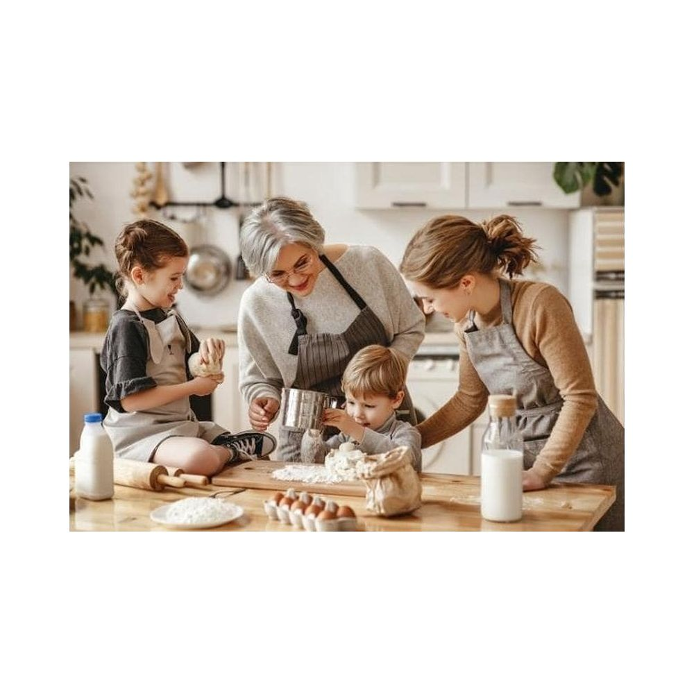 Una nonna, madre e due bambini cucinano insieme in una cucina luminosa.