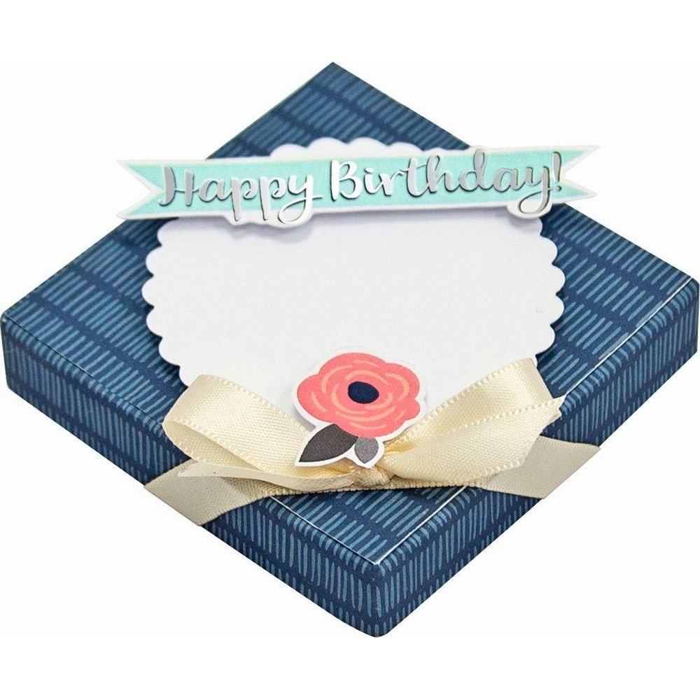 Niebieskie pudełko prezentowe z wstążką i kwiatkiem, napis 'Happy Birthday'.