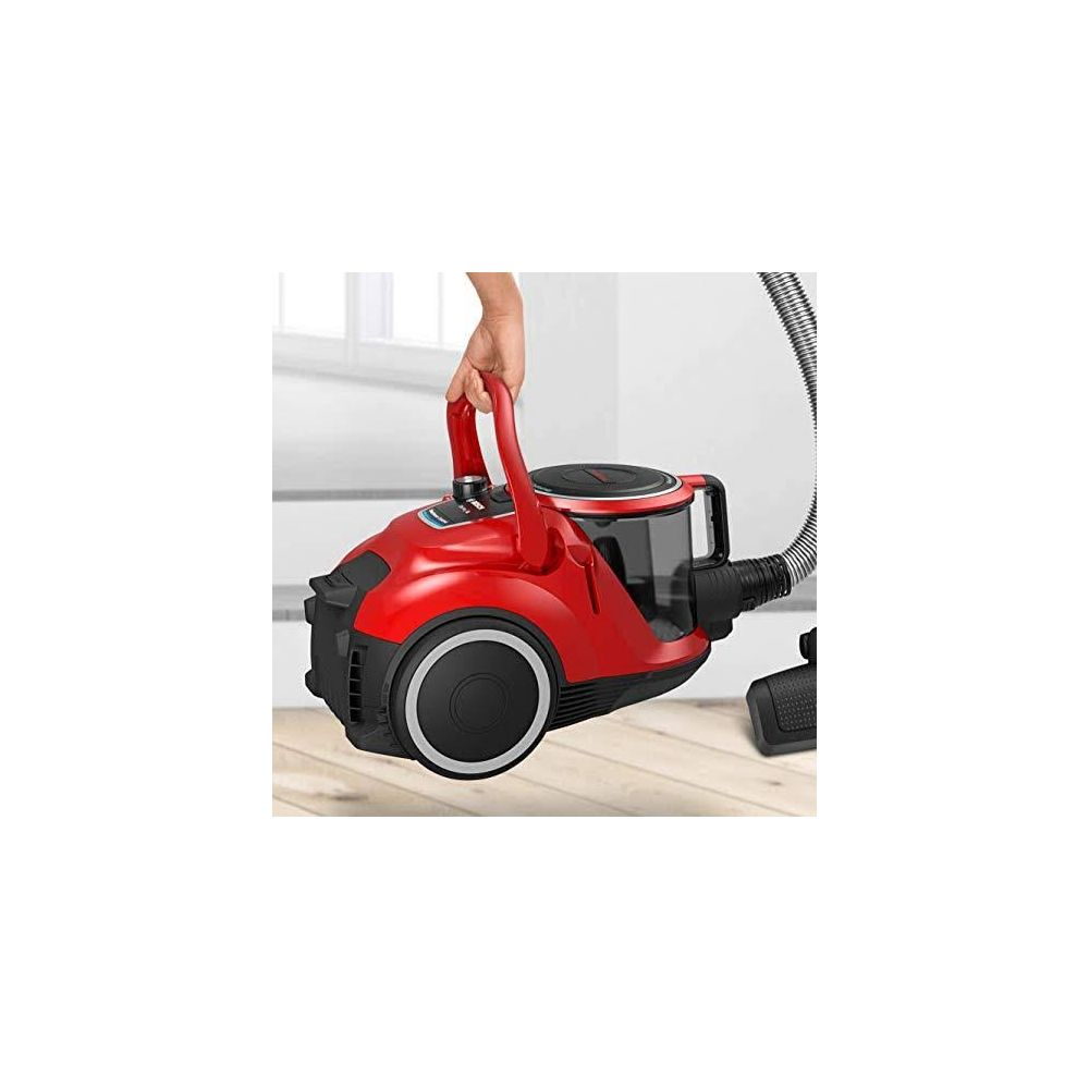 Czerwony odkurzacz z uchwytem jest trzymany przez rękę.