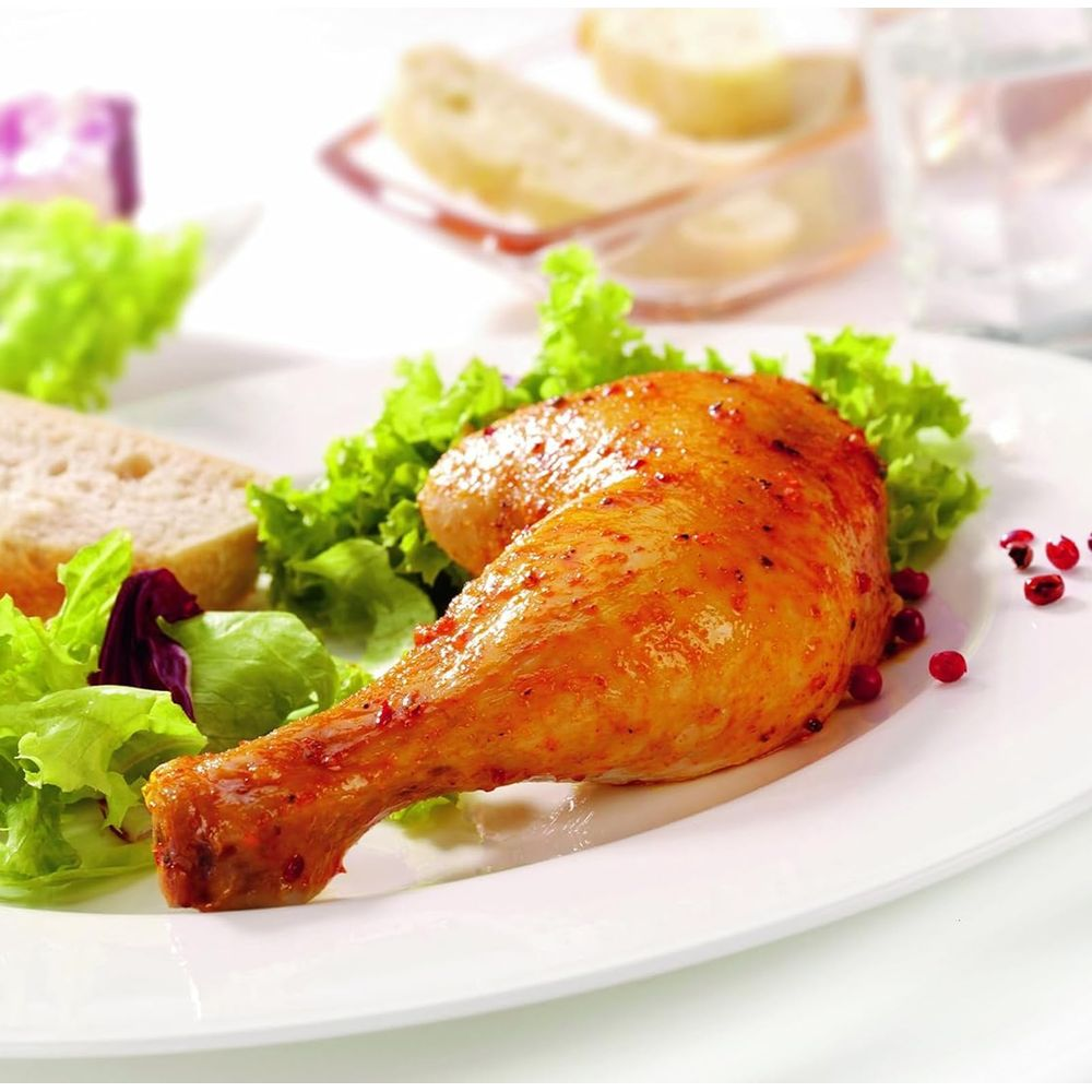 Cuisse de poulet rôtie avec salade et pain sur une assiette blanche.