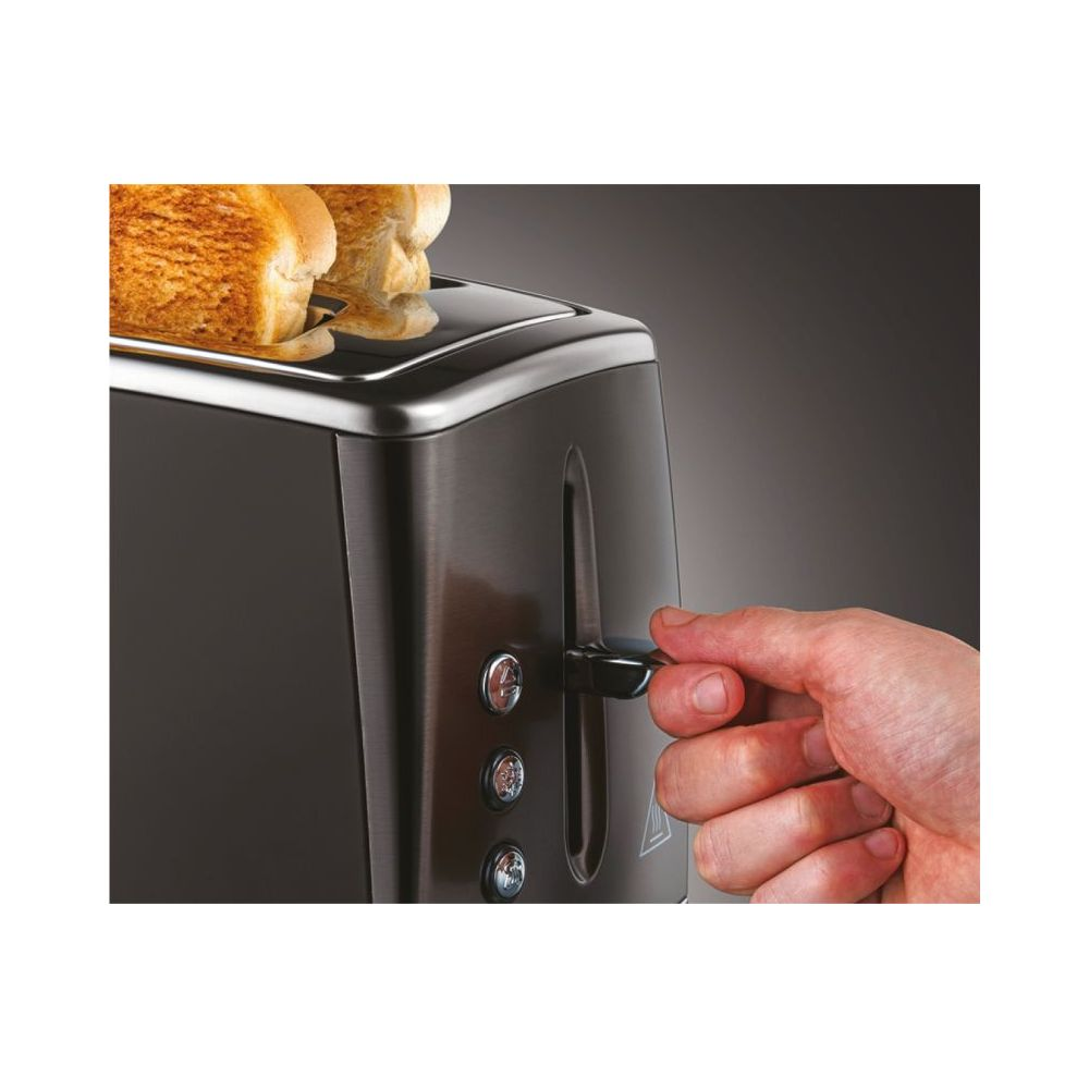 Eine Hand senkt einen Hebel an einem dunkelgrauen Toaster mit zwei Scheiben goldbraunem Toast.