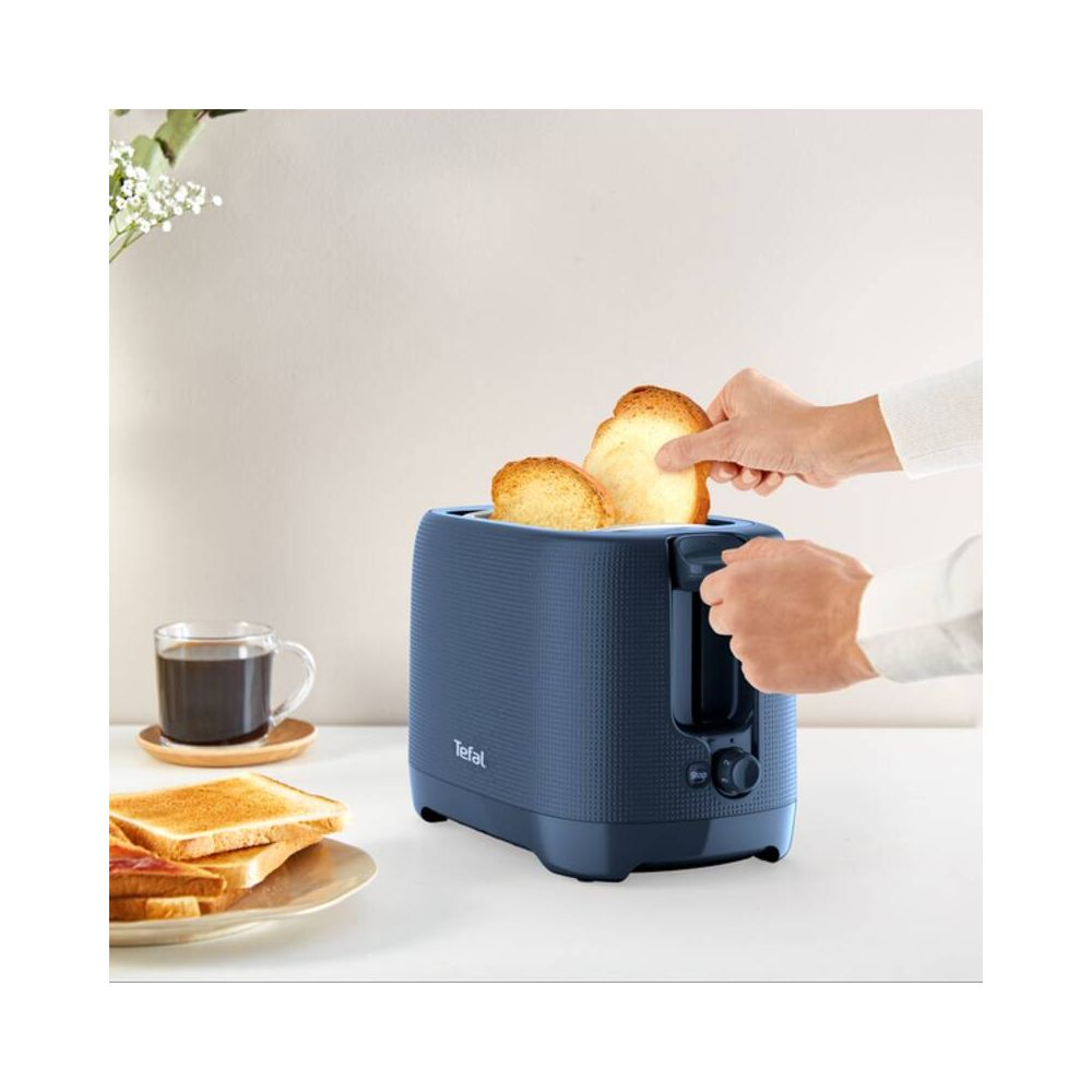 Blauer Toaster mit zwei Scheiben Toast, eine Hand legt Toast ein.