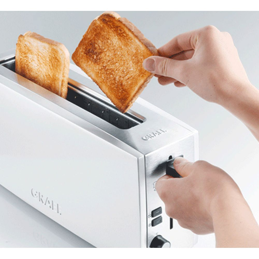 Eine Hand nimmt Toast aus einem weißen Toaster, ein zweiter Toast ist im Schlitz.