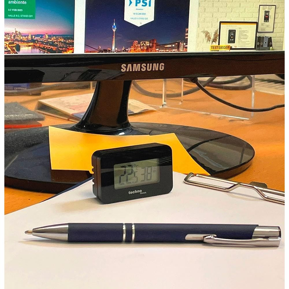 Ein dunkler Stift, ein Thermometer und eine Brille liegen auf einem Schreibtisch.