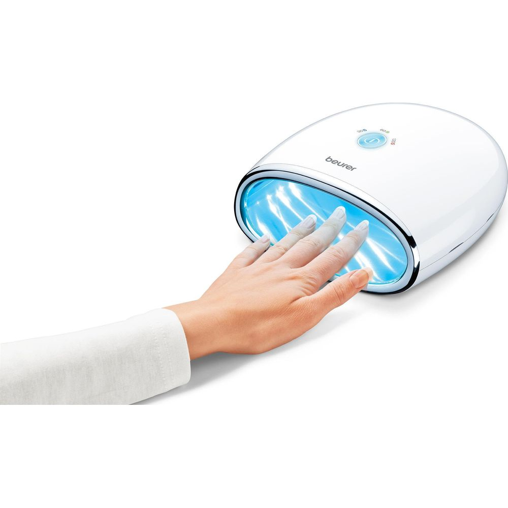 Eine Hand trocknet ihre Nägel unter einer weißen UV-Lampe mit blauen Lichtern.