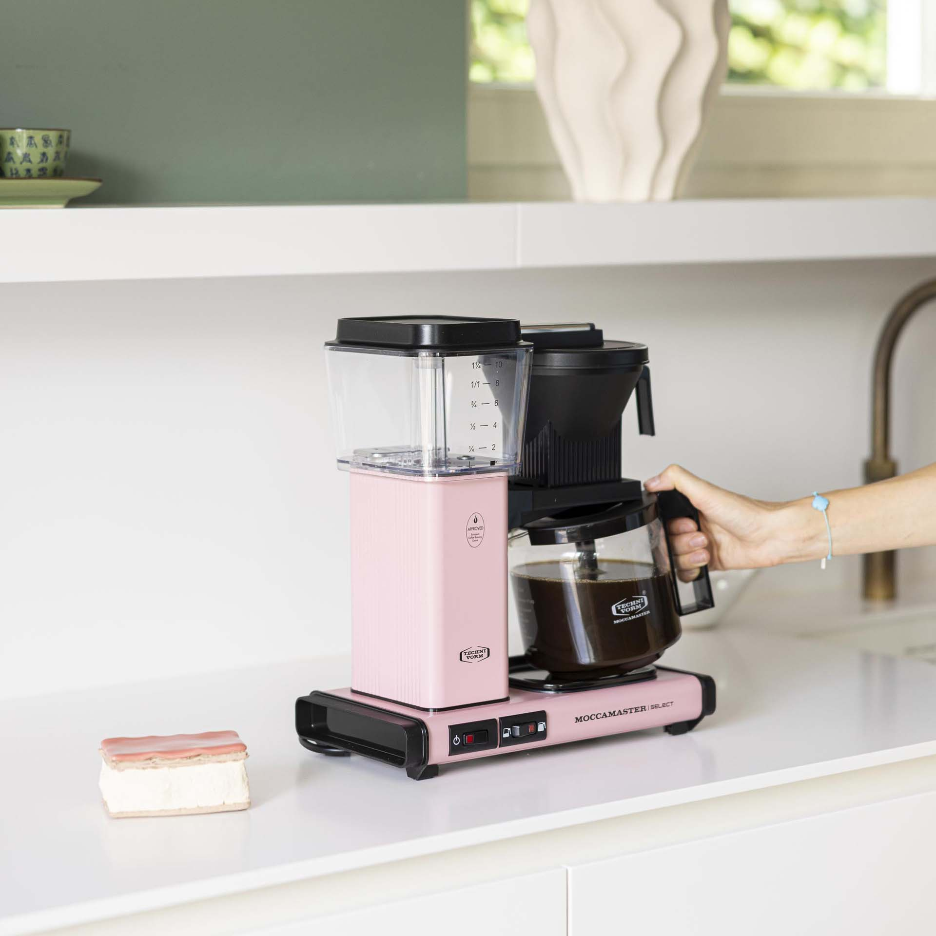 Eine pinke Moccamaster-Kaffeemaschine mit einer Glas Karaffe voller Kaffee.