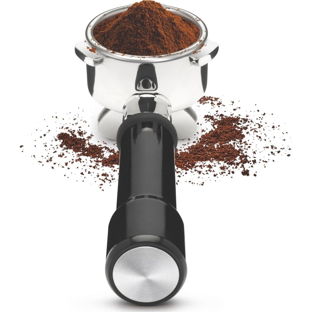 Un porte-filtre rempli de café moulu, avec des grains de café éparpillés.