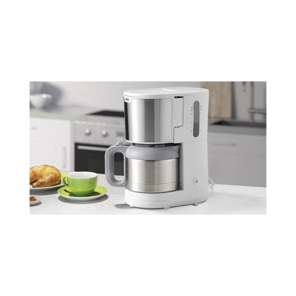 Biały ekspres do kawy z termosem, obok rogalika i zielonej filiżanki.