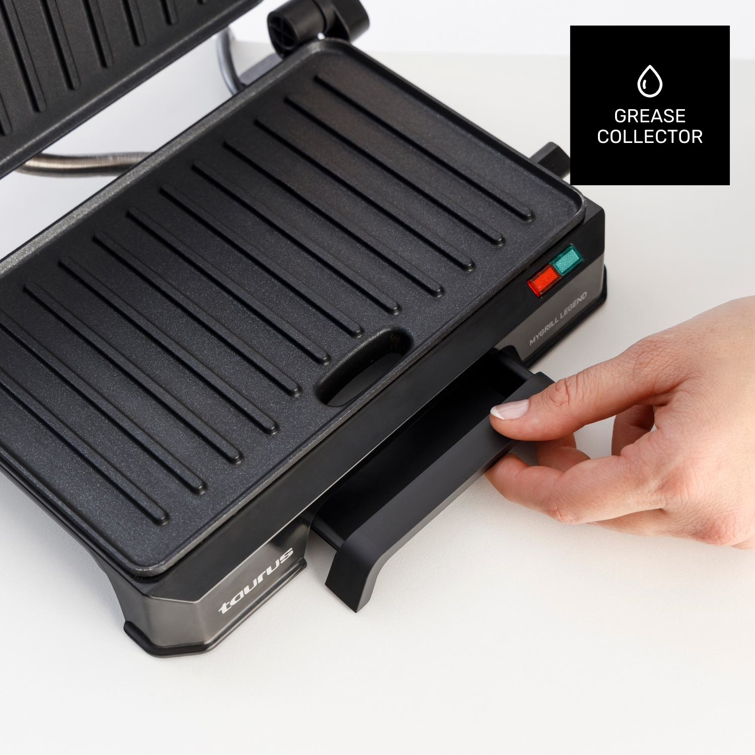 Dłoń wyciąga tacę na tłuszcz z czarnego grilla kontaktowego.