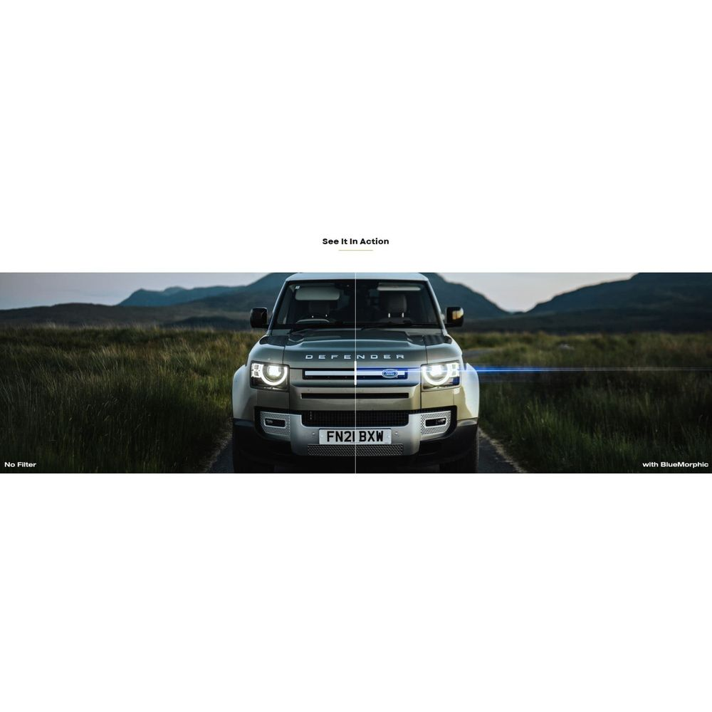 Un Land Rover Defender argenté est garé sur une route, avec des montagnes en arrière-plan.