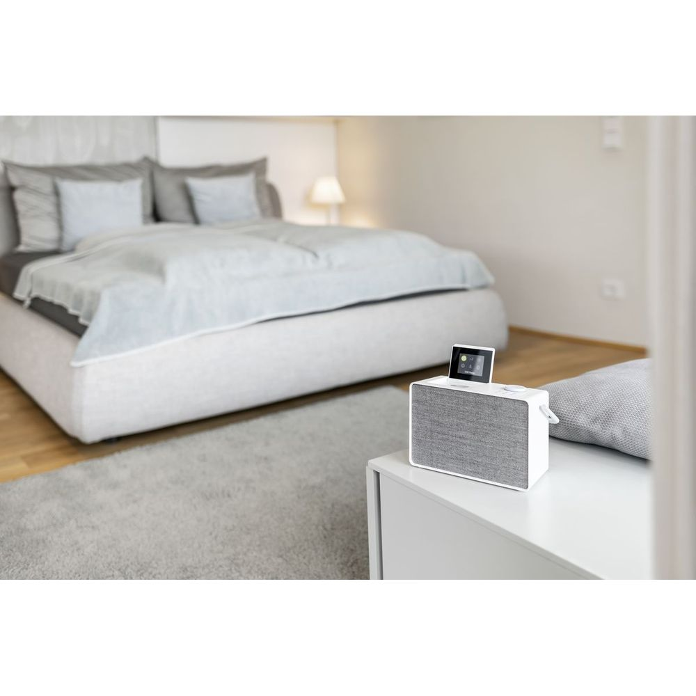 Modernes Schlafzimmer mit einem Bett und einem Nachttisch mit weißem Lautsprecher.