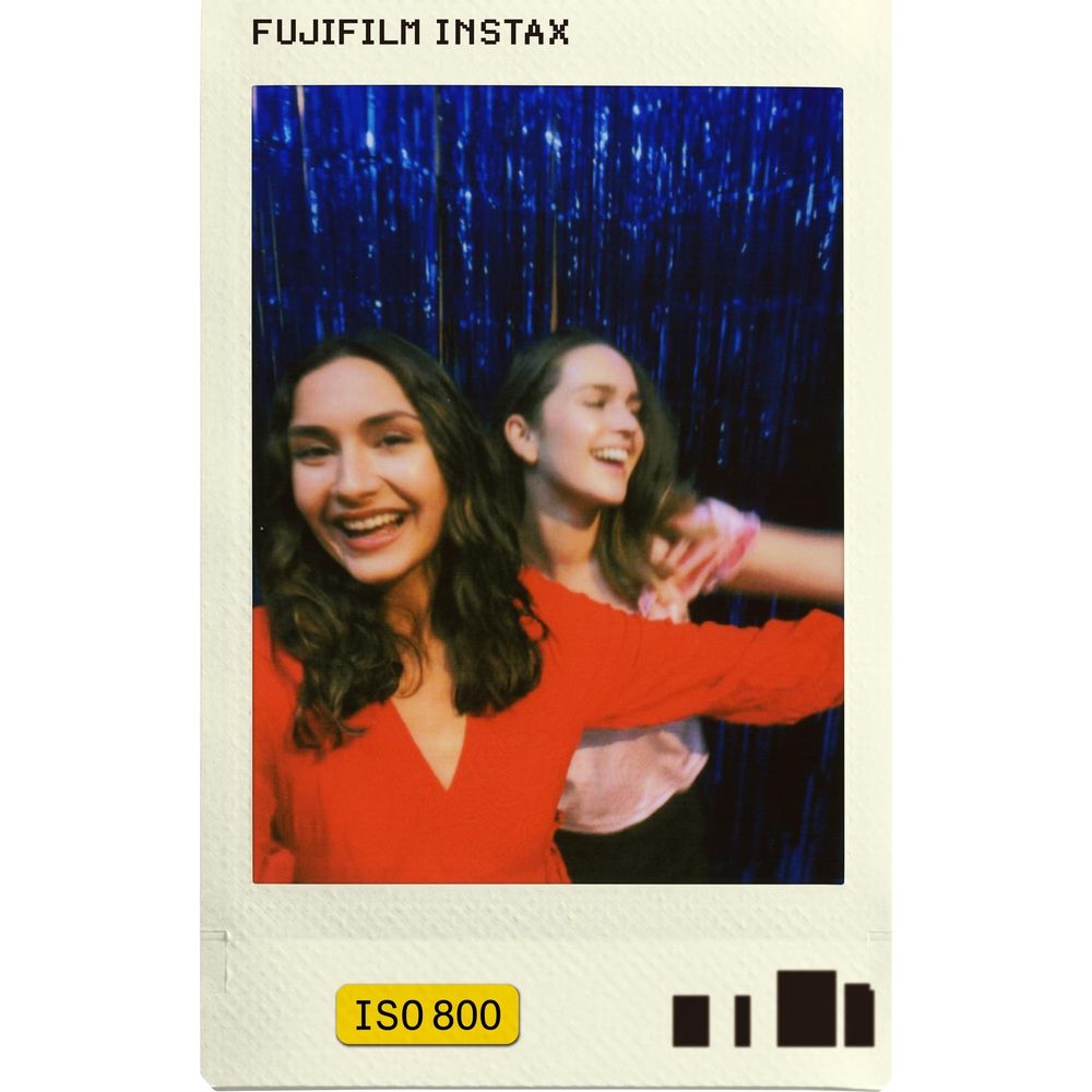 Dos mujeres jóvenes ríen ante una cortina de lentejuelas azules. Una de rojo.