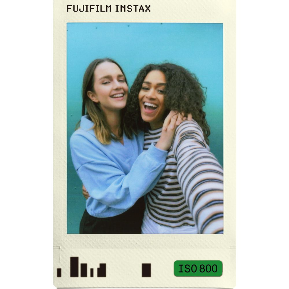 Dos mujeres riendo se abrazan frente a una pared azul. Fujifilm Instax.