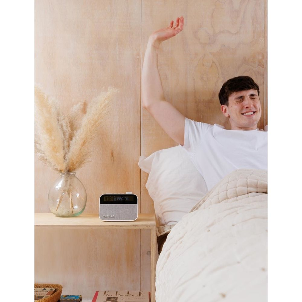Un hombre se estira en la cama, una radio en la mesita de noche.