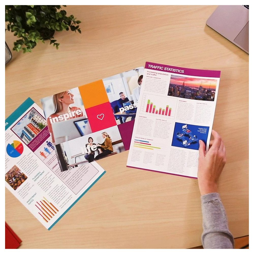 Widok z góry na biurko z dokumentami i ręką trzymającą kartkę.