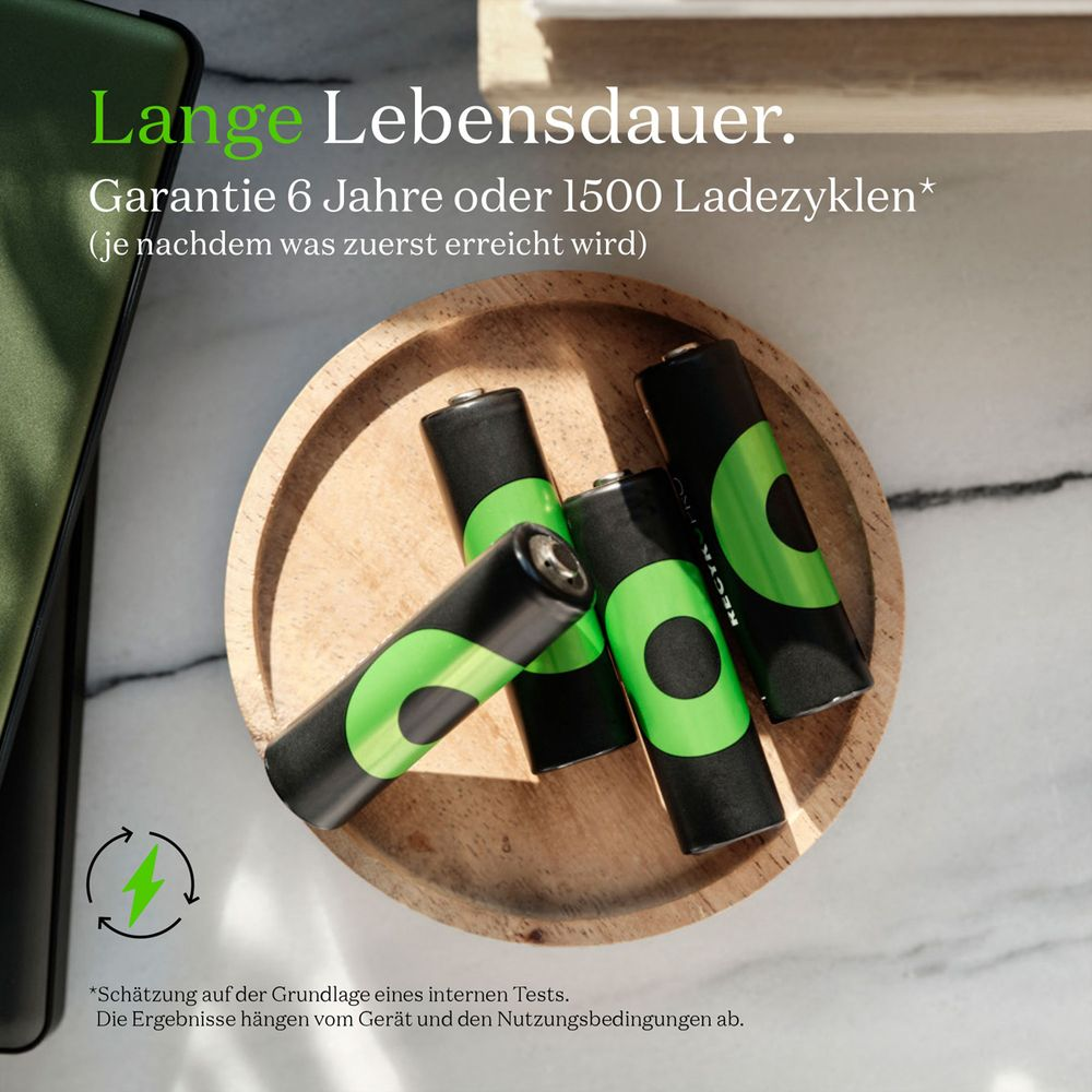 Cztery czarne baterie z zielonymi pierścieniami leżą na drewnianym talerzu.