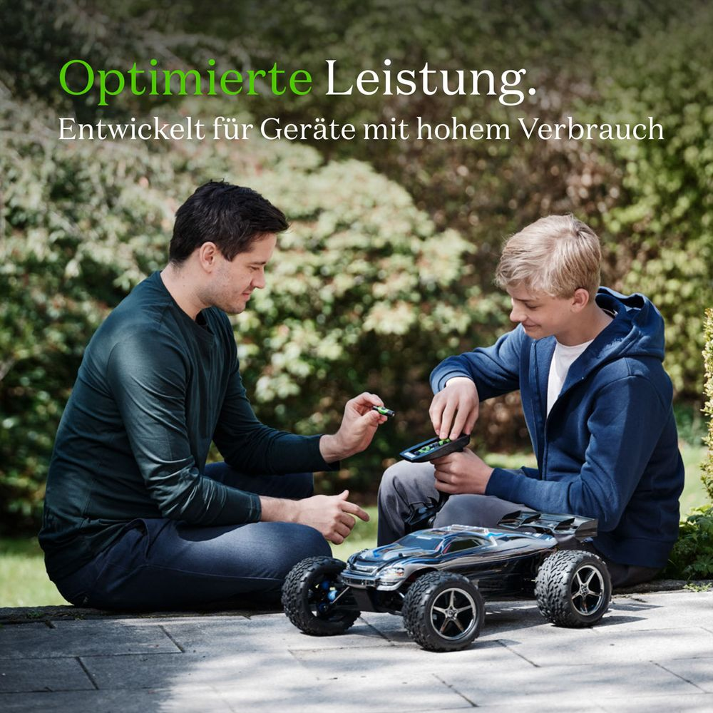 Mężczyzna i chłopiec siedzą na zewnątrz, bawiąc się pilotem i samochodem-zabawką.