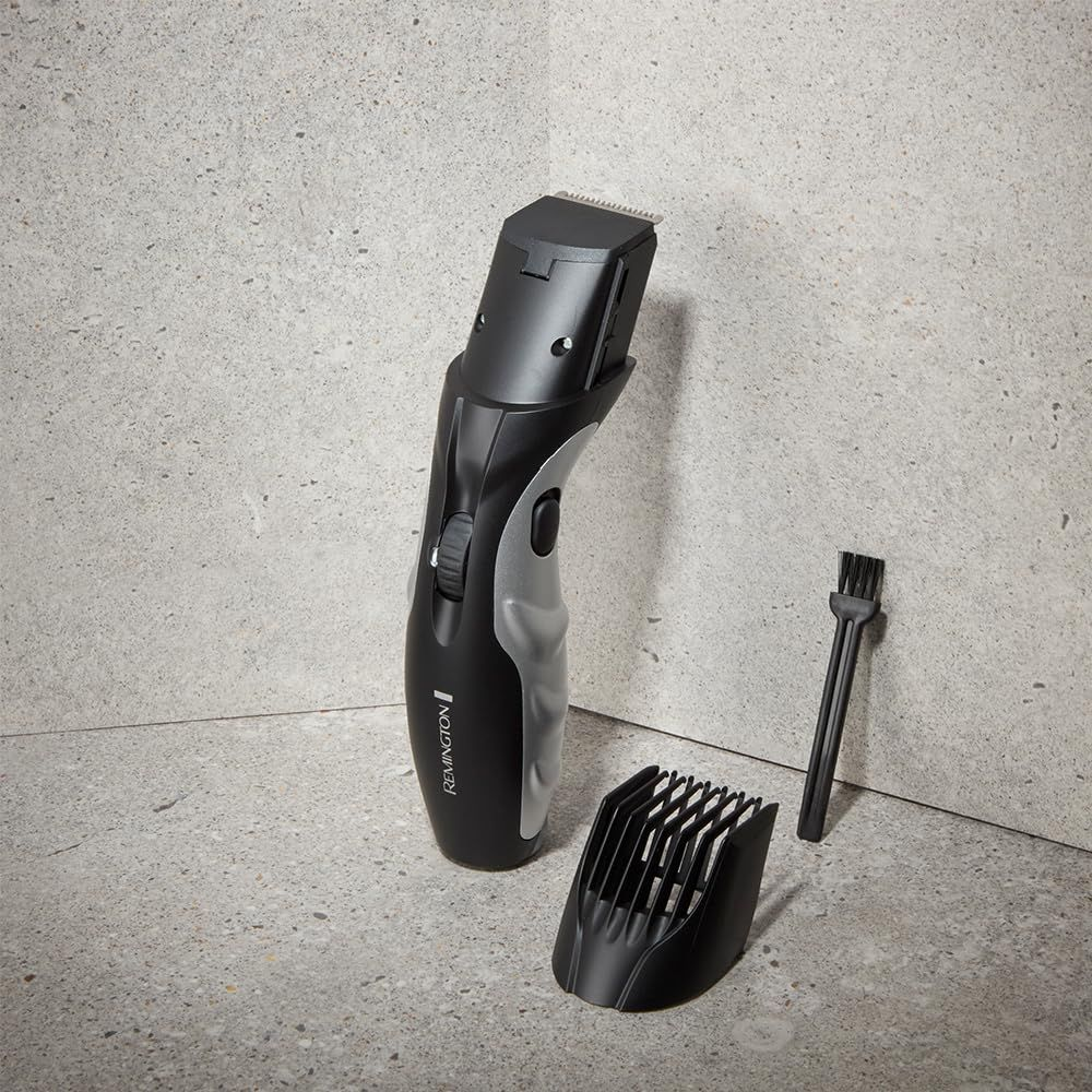 Una cortapelos Remington negra con detalles plateados, un accesorio de peine y un cepillo.