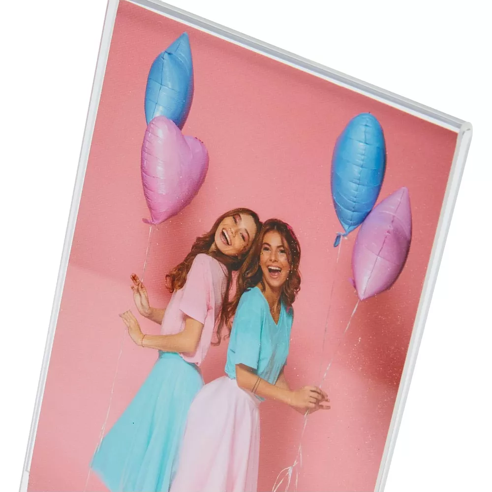 Zwei lachende Frauen mit Luftballons vor rosa Hintergrund.