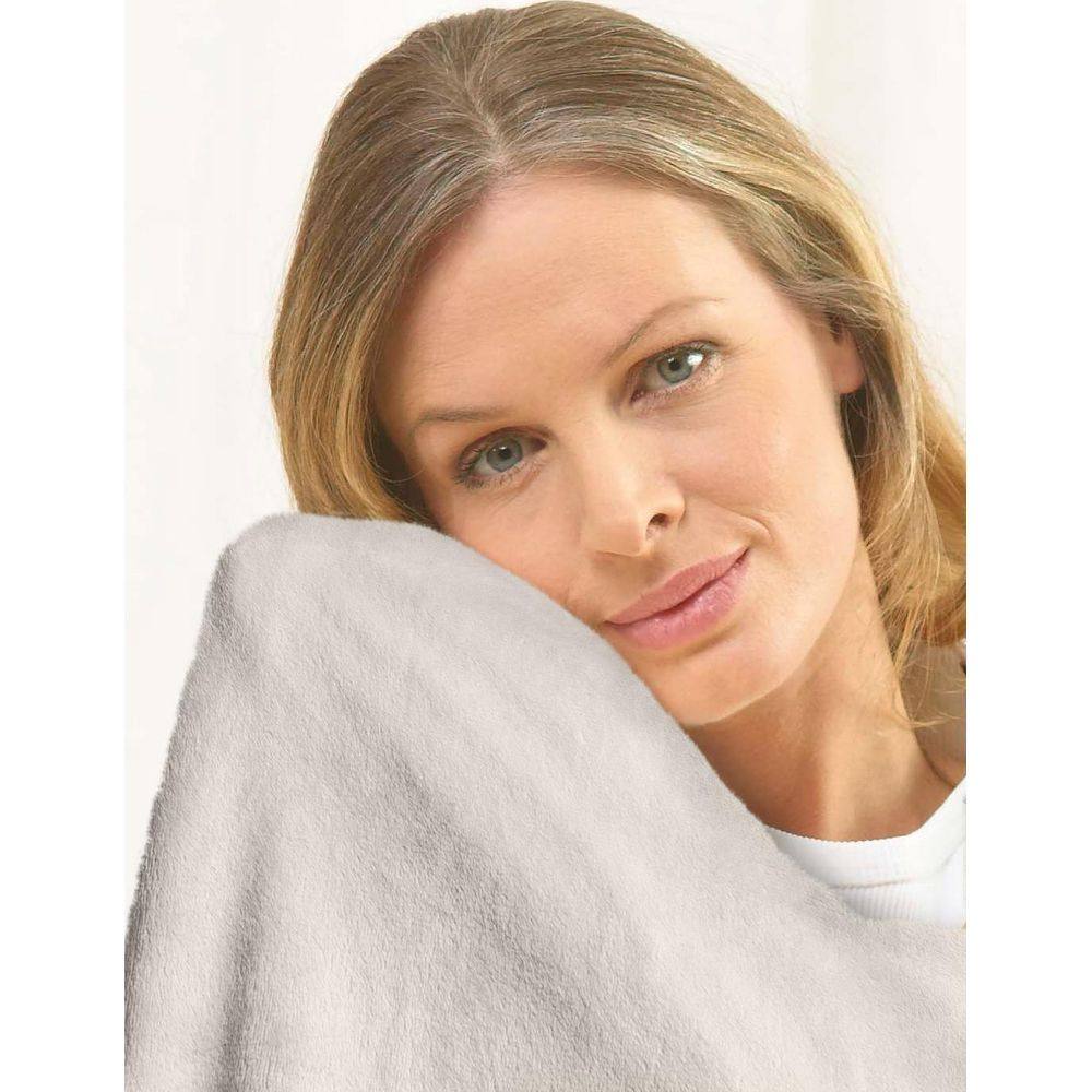 Una donna bionda appoggia la testa su una morbida coperta color crema.