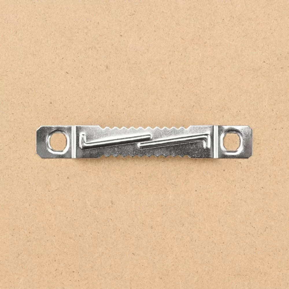 Srebrny wieszak z zębami piły z dwoma otworami montażowymi na brązowym tle.