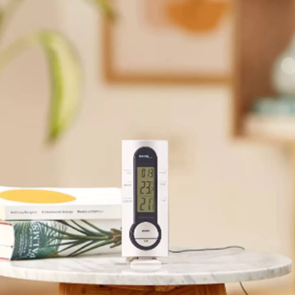 Cyfrowy termometr pokazuje 0.13, 23.0 i 21.0. Obok leżą książki.