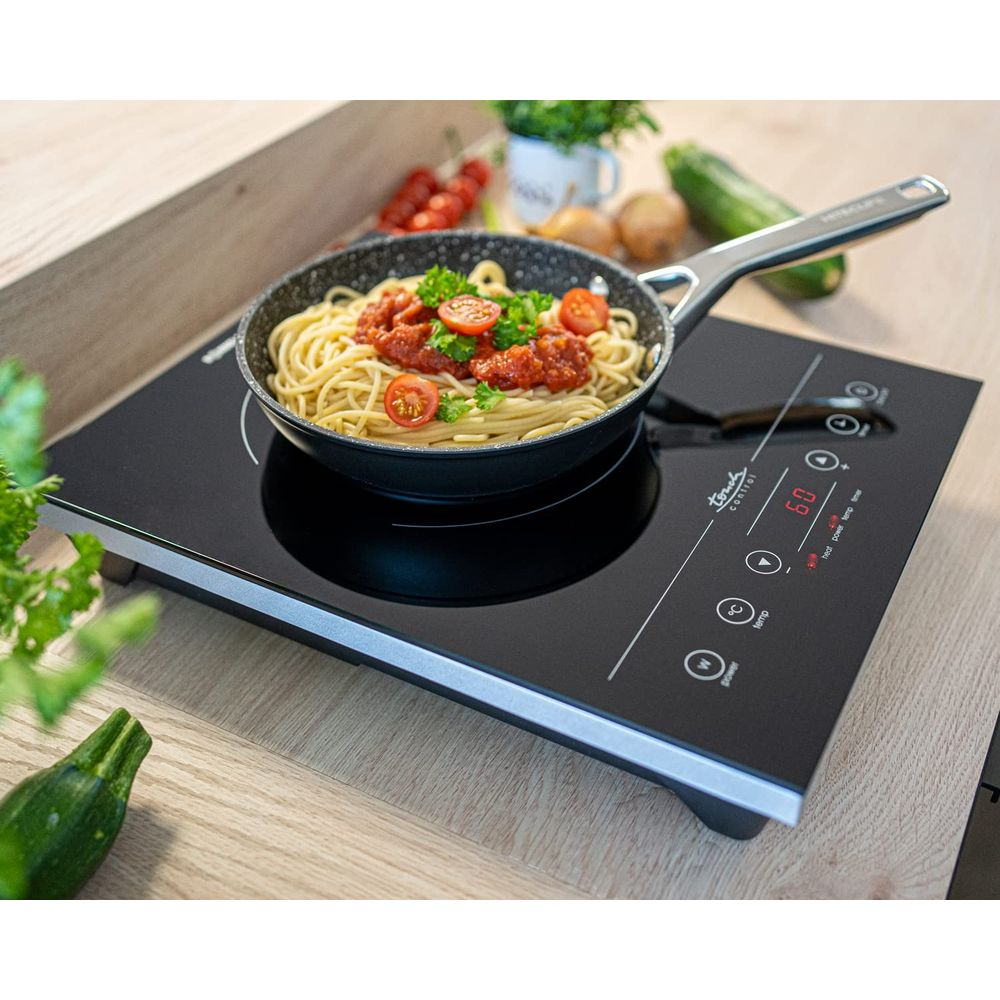 Spaghetti z sosem pomidorowym na patelni na płycie indukcyjnej.