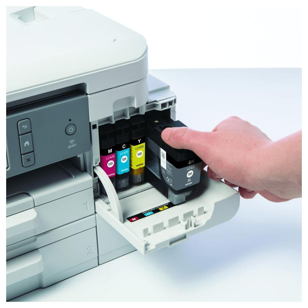 Ręka wkłada czarny tusz do drukarki z widocznymi tuszami magenta, cyjan, żółtym.