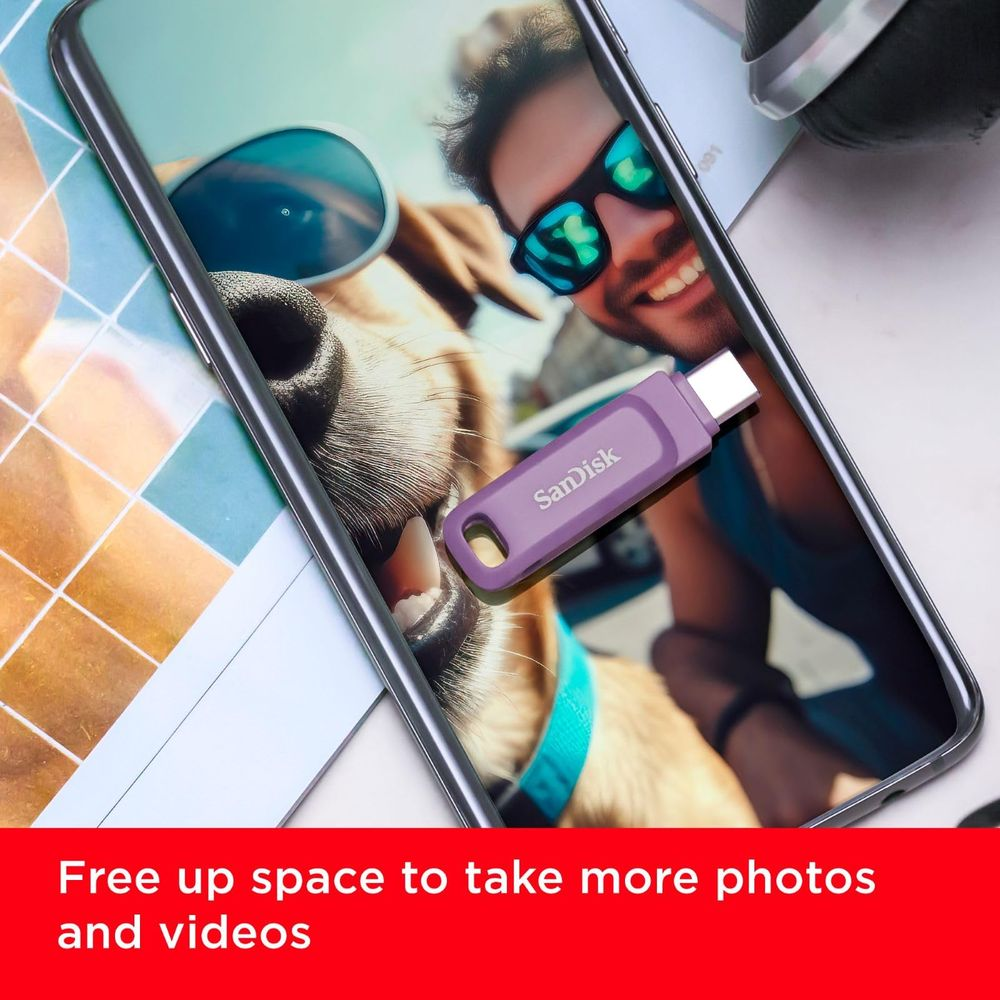 Fioletowy pendrive SanDisk na smartfonie wyświetlający zdjęcie mężczyzny i psa.
