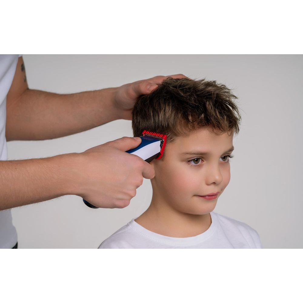 Ein Junge bekommt die Haare mit einem blauen und weißen Haarschneider geschnitten.