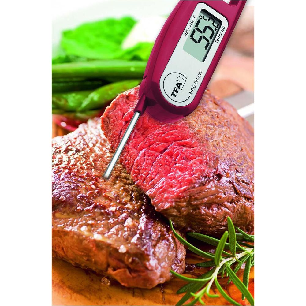 Un thermomètre à viande numérique mesure la température d'un steak cru.