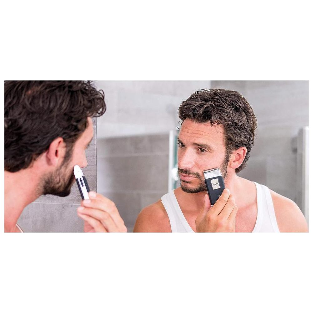 Mężczyzna goli się w lustrze trymerem WAHL i małym trymerem do włosów w nosie.