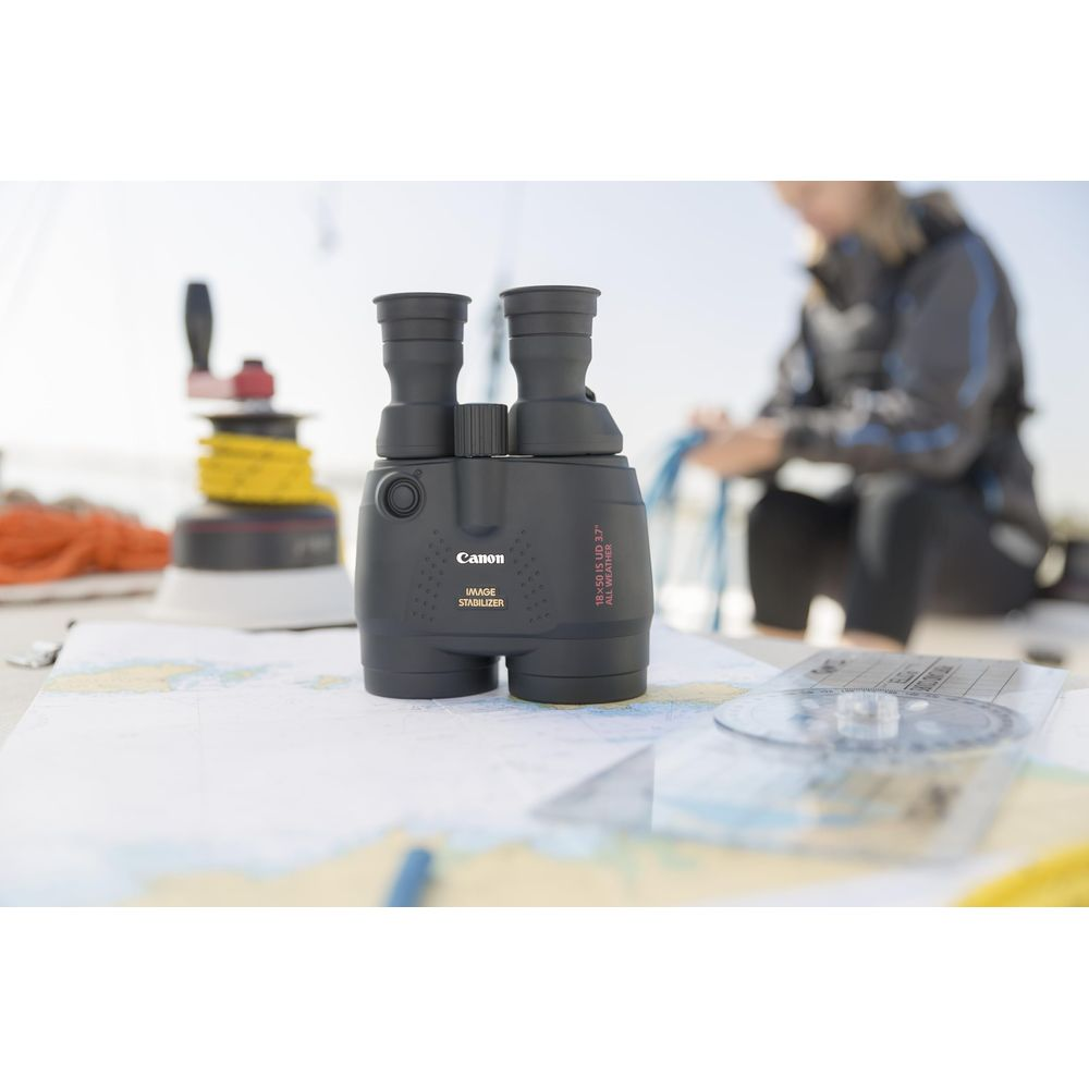 Lornetka na mapie morskiej z kompasem i osobą w tle.