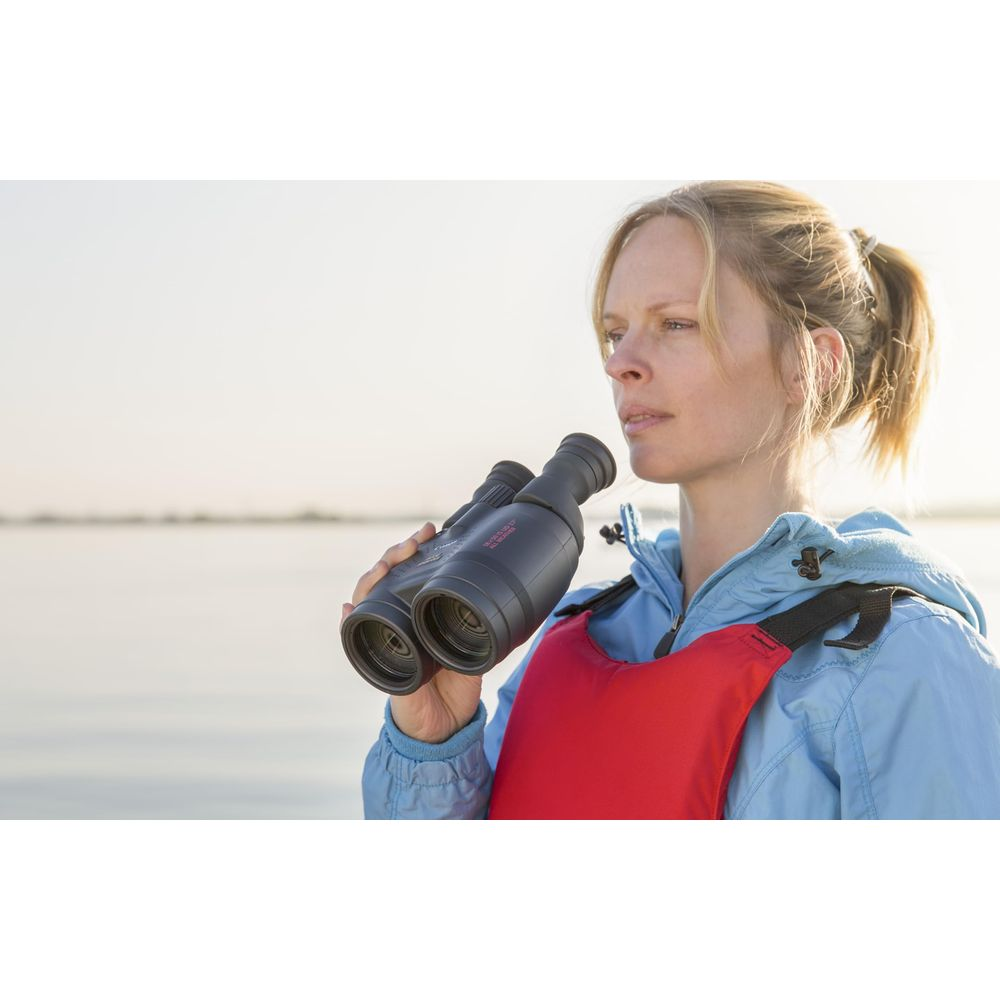 Kobieta z lornetką i kamizelką ratunkową na wodzie.