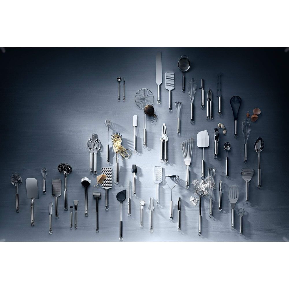 Una collezione di utensili da cucina, inclusi fruste e spatole, su sfondo grigio.