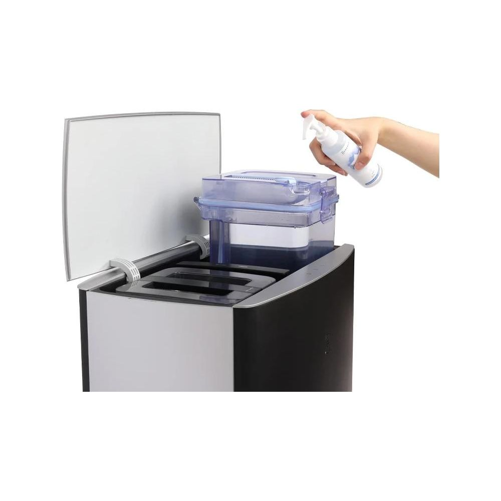 Ręka rozpyla płyn do maszyny z przezroczystym pojemnikiem.