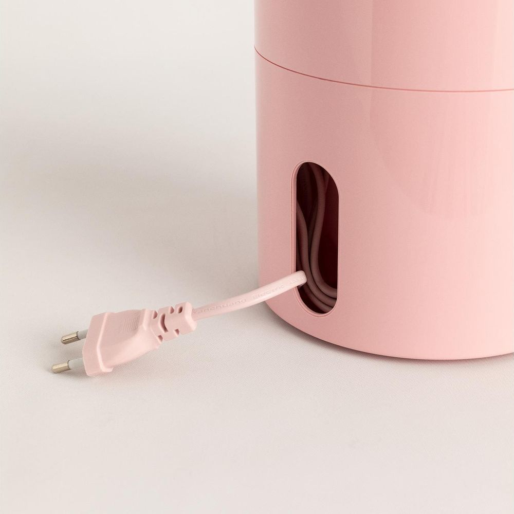 Un cavo di alimentazione rosa esce da un contenitore rotondo rosa.