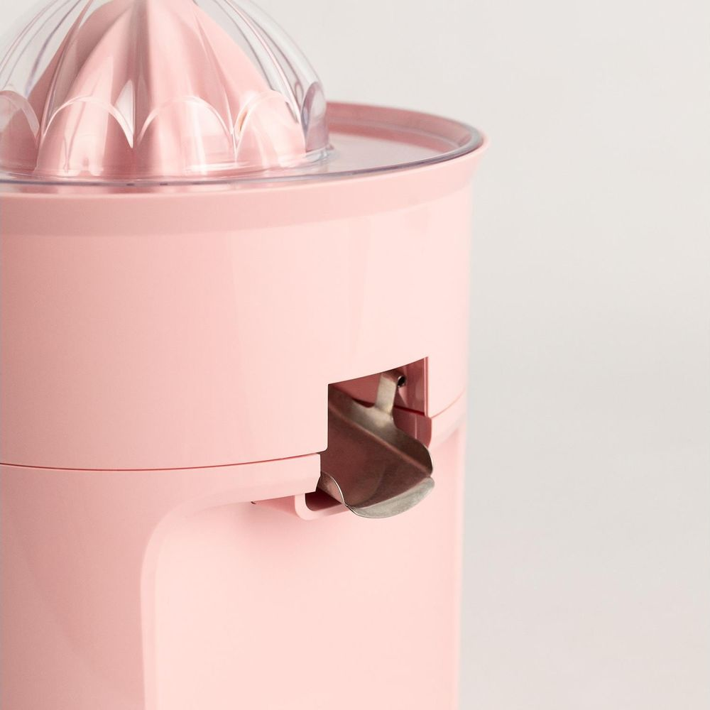 Un spremiagrumi rosa con coperchio trasparente e beccuccio.