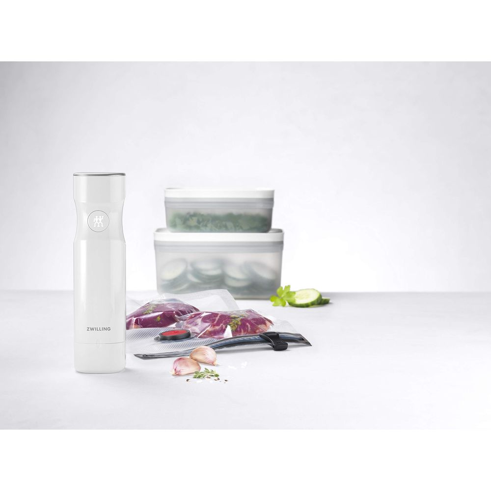 Biała zgrzewarka próżniowa z dwoma pojemnikami i mięsem zapakowanym próżniowo na stole.