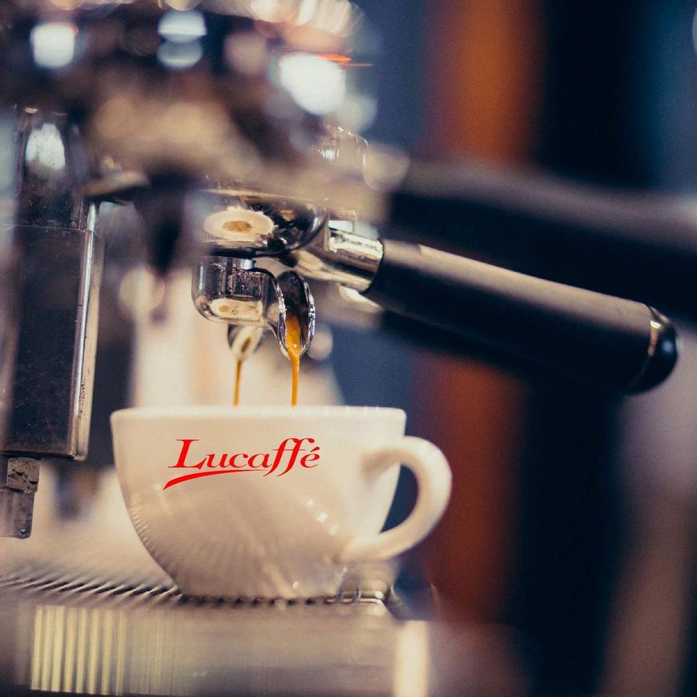 Ein Espresso fließt aus einer Maschine in eine weiße Tasse mit rotem Schriftzug.