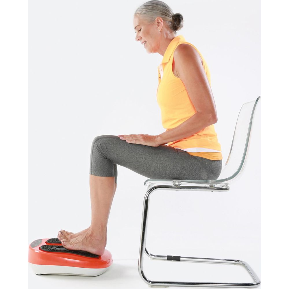 Une femme âgée est assise sur une chaise avec une plaque vibrante sous ses pieds.