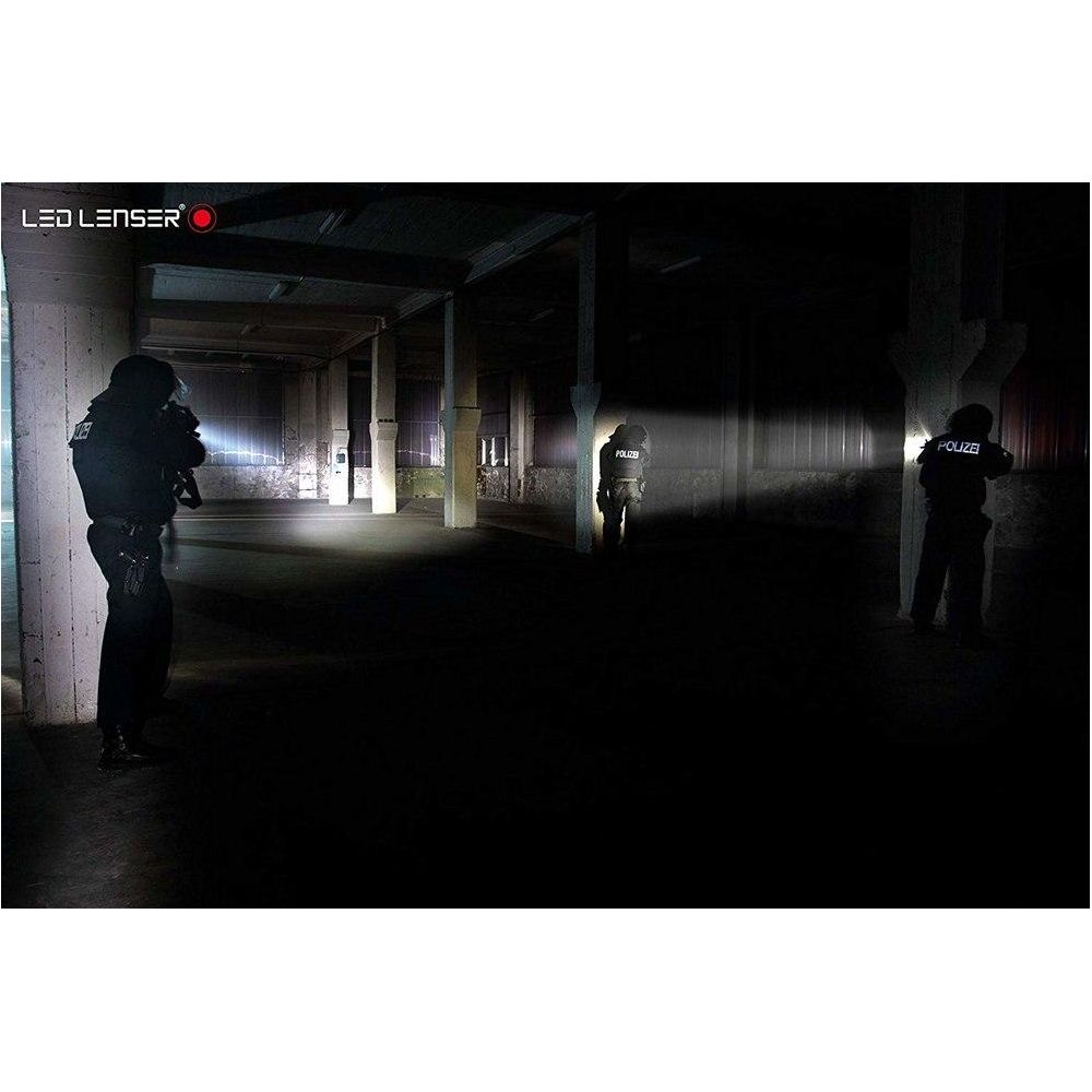 Policjanci oświetlają ciemną halę latarkami.